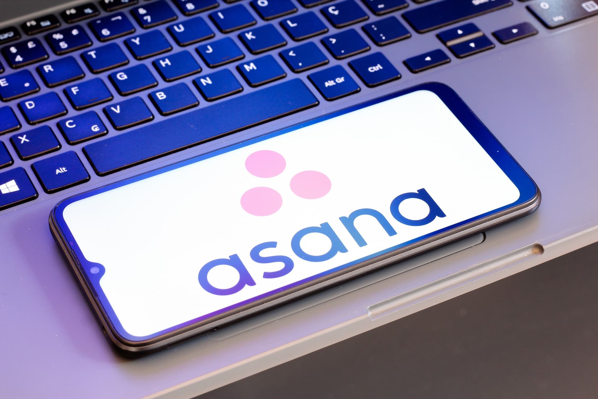 Asana-ს ლოგო და AI ტექნოლოგიების სიმბოლური გამოსახულება